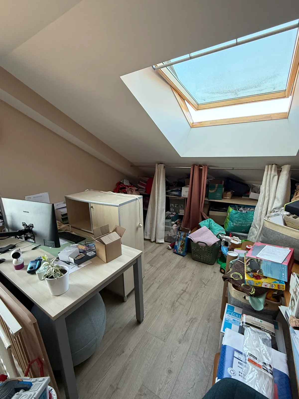 Vue d'ensemble du bureau sous les combles avant le tri, sol et meubles encombrés