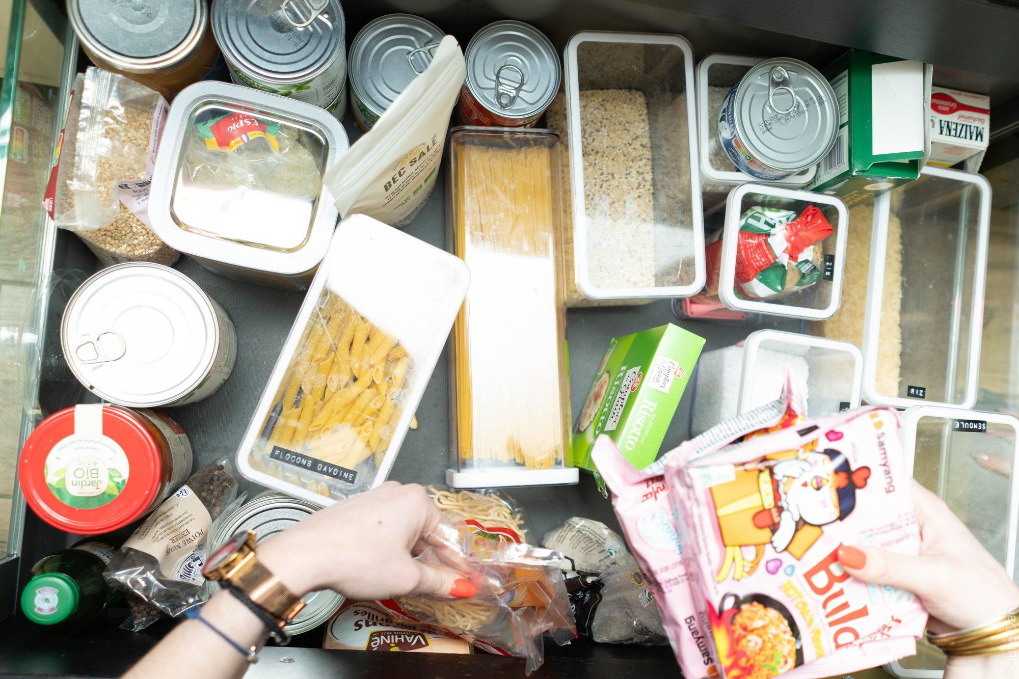 Tiroir de cuisine organisé avec des boîtes transparentes, vu de dessus