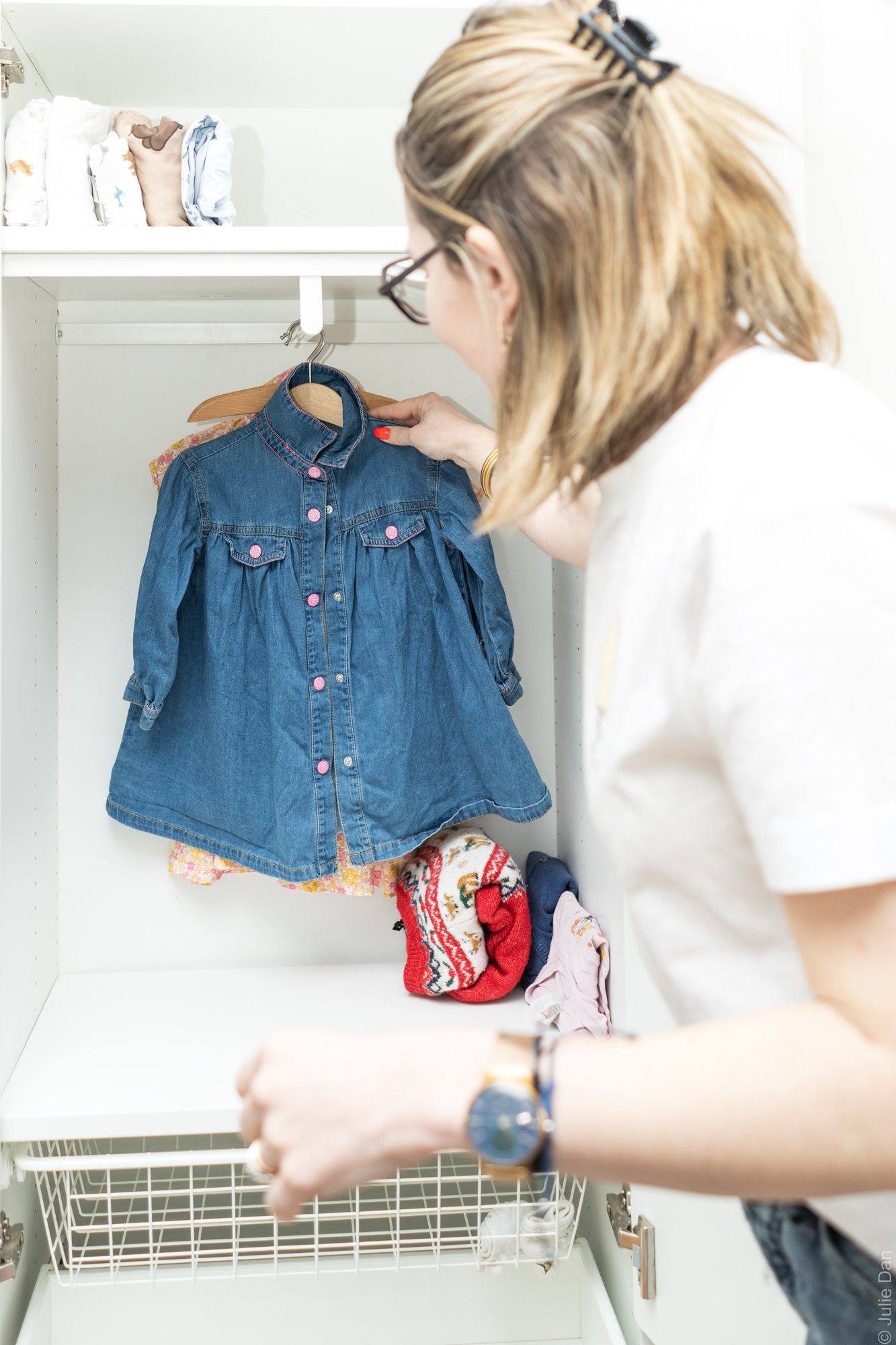 Virginie Pinsault range une robe en jean dans le placard d'une chambre d'enfant