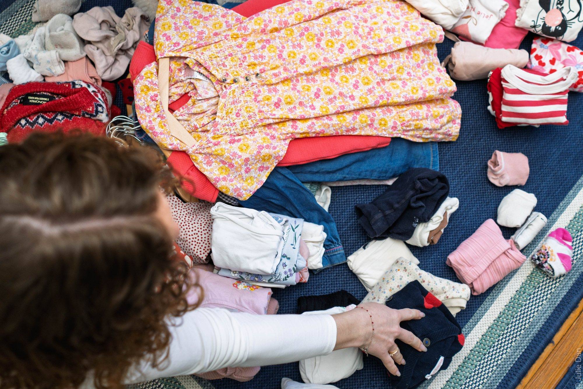 Piles de petits vêtements triés sur un tapis bleu