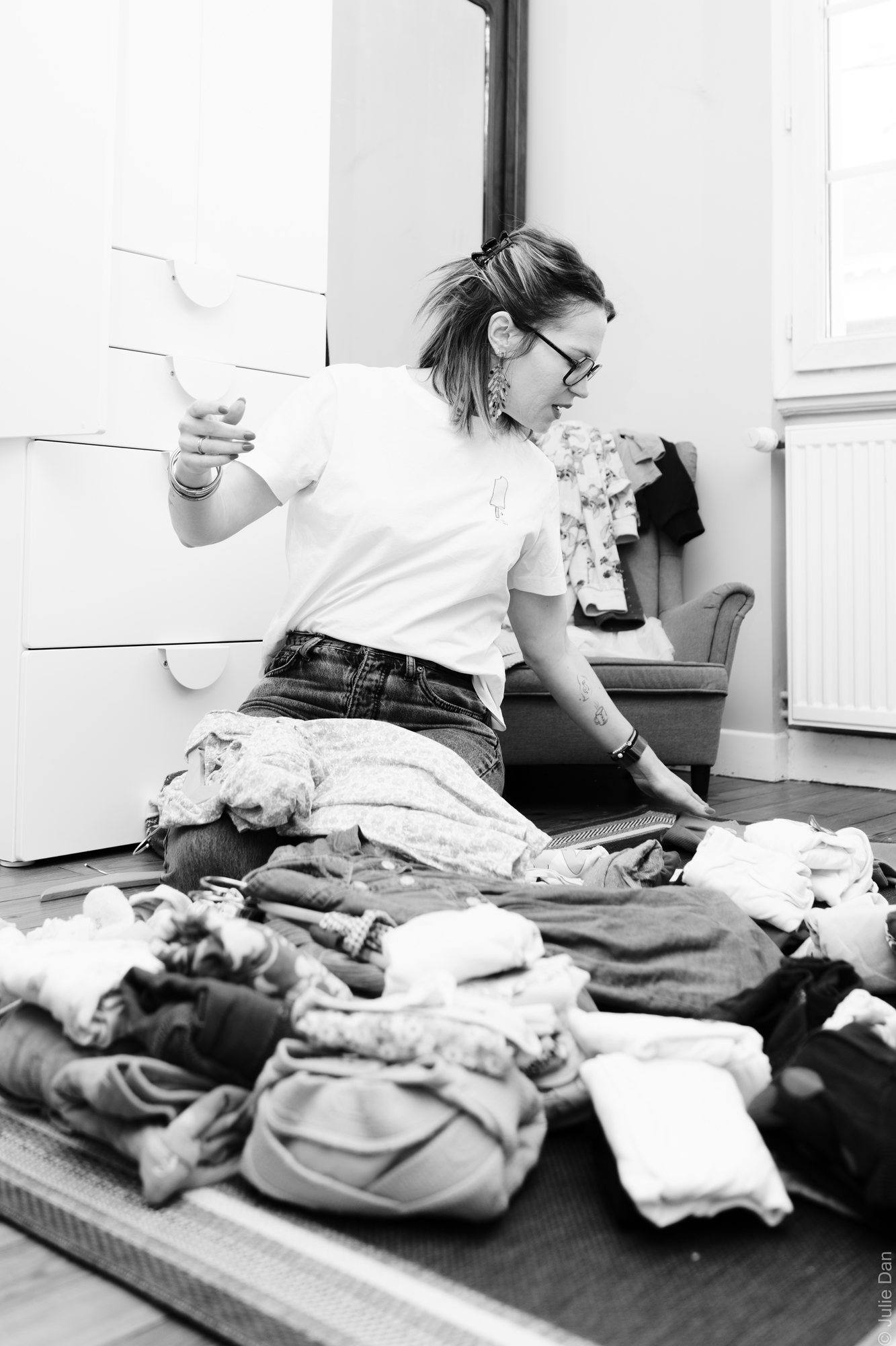 Virginie Pinsault trie une pile de vêtements, photo en noir et blanc
