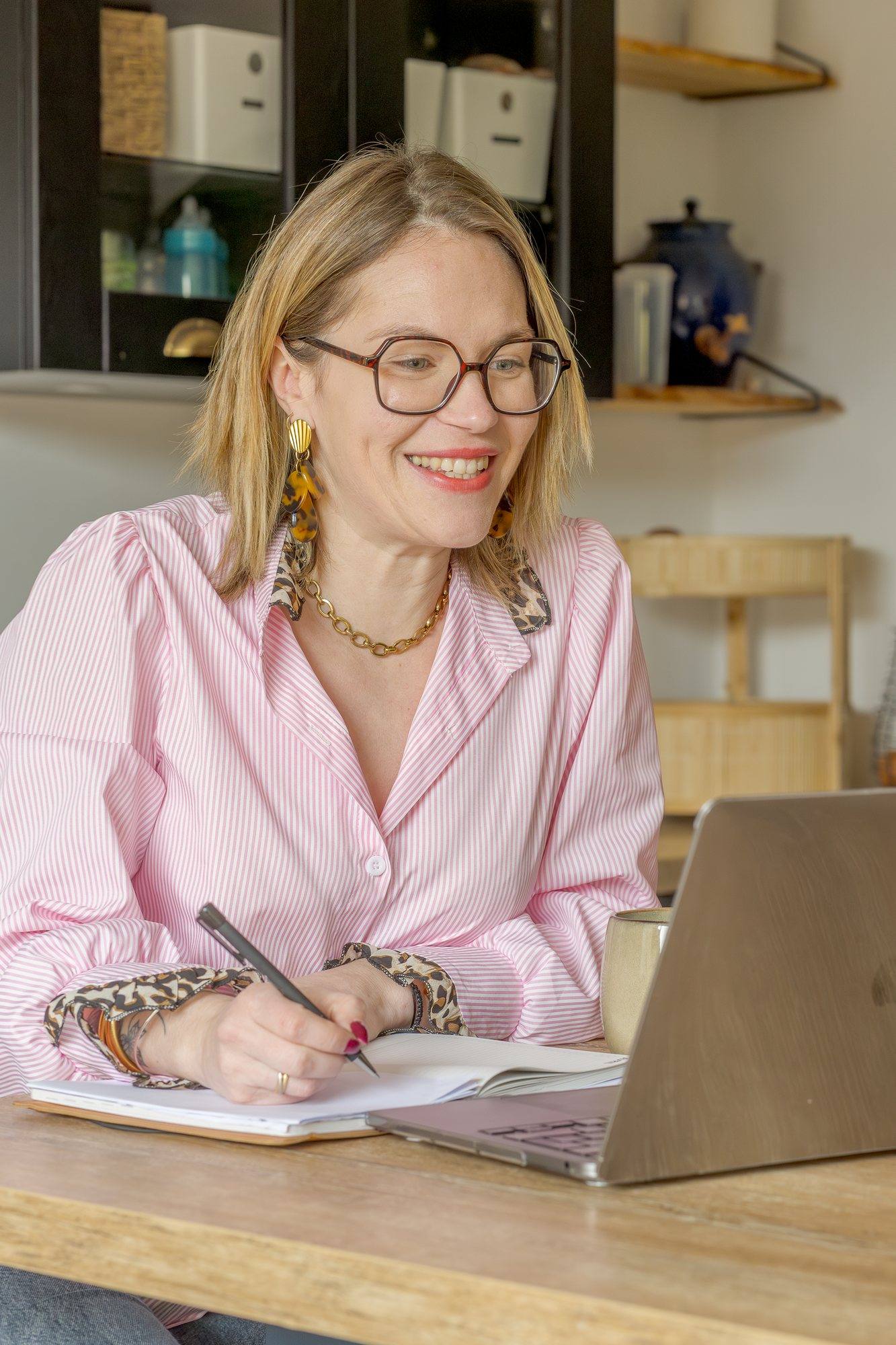 Virginie Pinsault souriante à son bureau, un carnet et un ordinateur devant elle