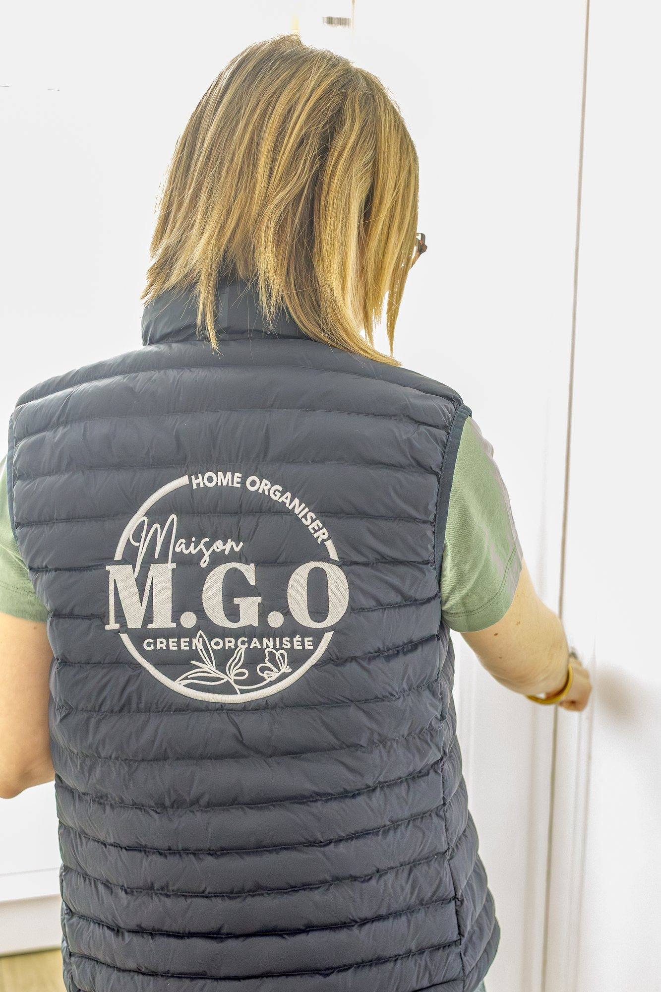 Virginie Pinsault de dos, doudoune sans manches floquée du logo Maison Green Organisée